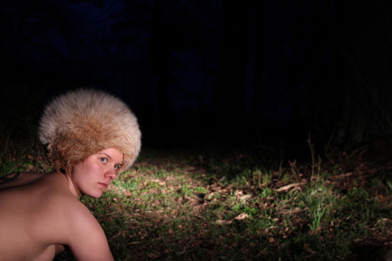 Photograph of a nude person from the chest up with a fur hat.